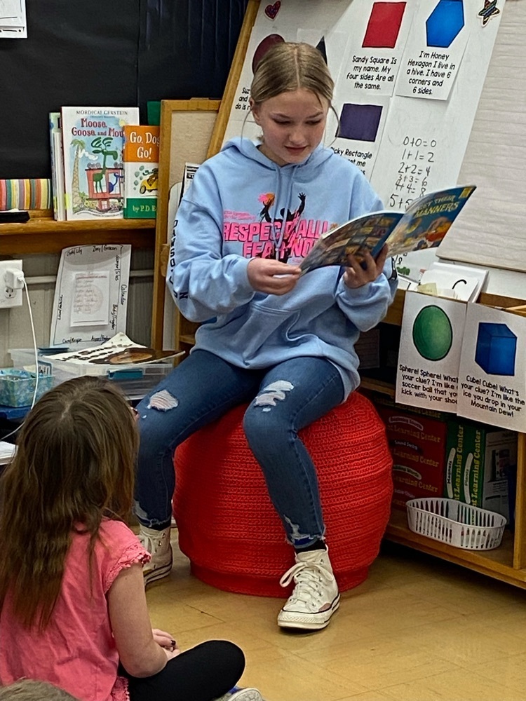 middle schooler reading to kindergarteners 